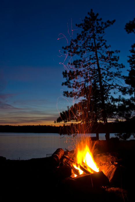 roaring campfire at night alongside a lake