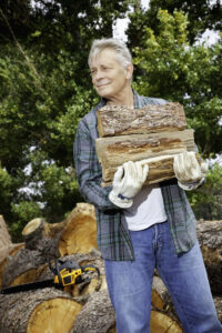 elderly man carrying firewood in his arms