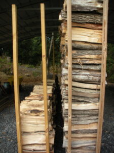 A pile of wood is stacked in the middle of two poles.