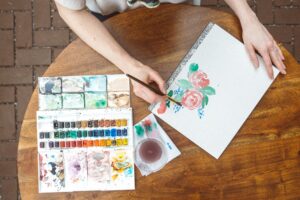 hands on table painting flowers in watercolors