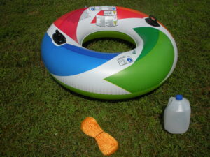 A colorful inflatable ring and a plastic container on the grass.