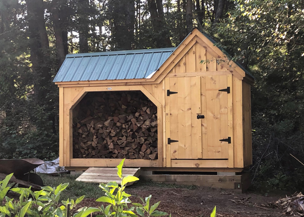 wooden firewood holder house with green metal roof and pull open doors
