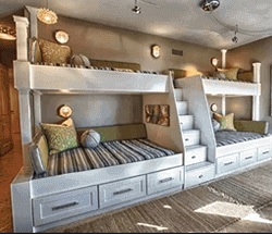 4 custom bunk beds connected with a small staircase leading up to 2 top beds located in a bedroom