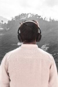A man wearing headphones looking out over the water.