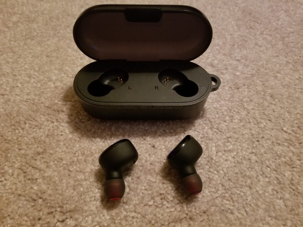 2 black earbuds with case on carpet floor