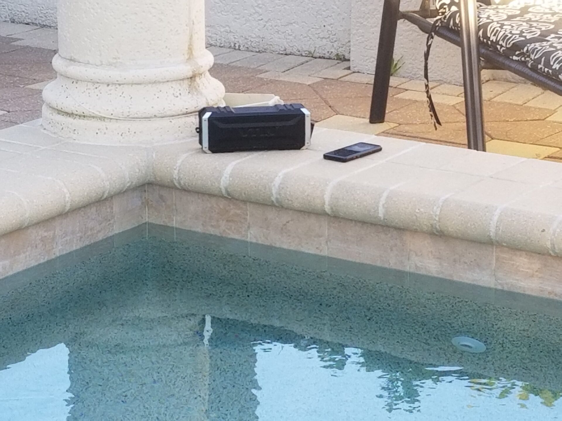 portable speaker and MP3 player on cement wall poolside