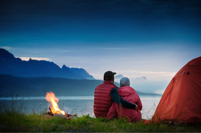 A couple sitting on the grass near some fire