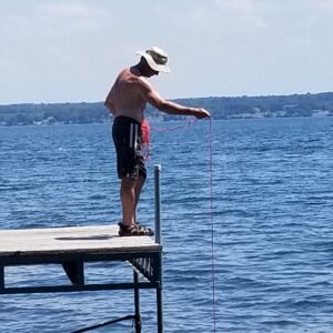 A man standing on the end of a pier fishing.