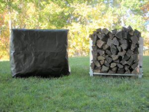 2 TFH-1 firewood racks sitting on grass one with firewood stacked and the other with a custom cover draped over it